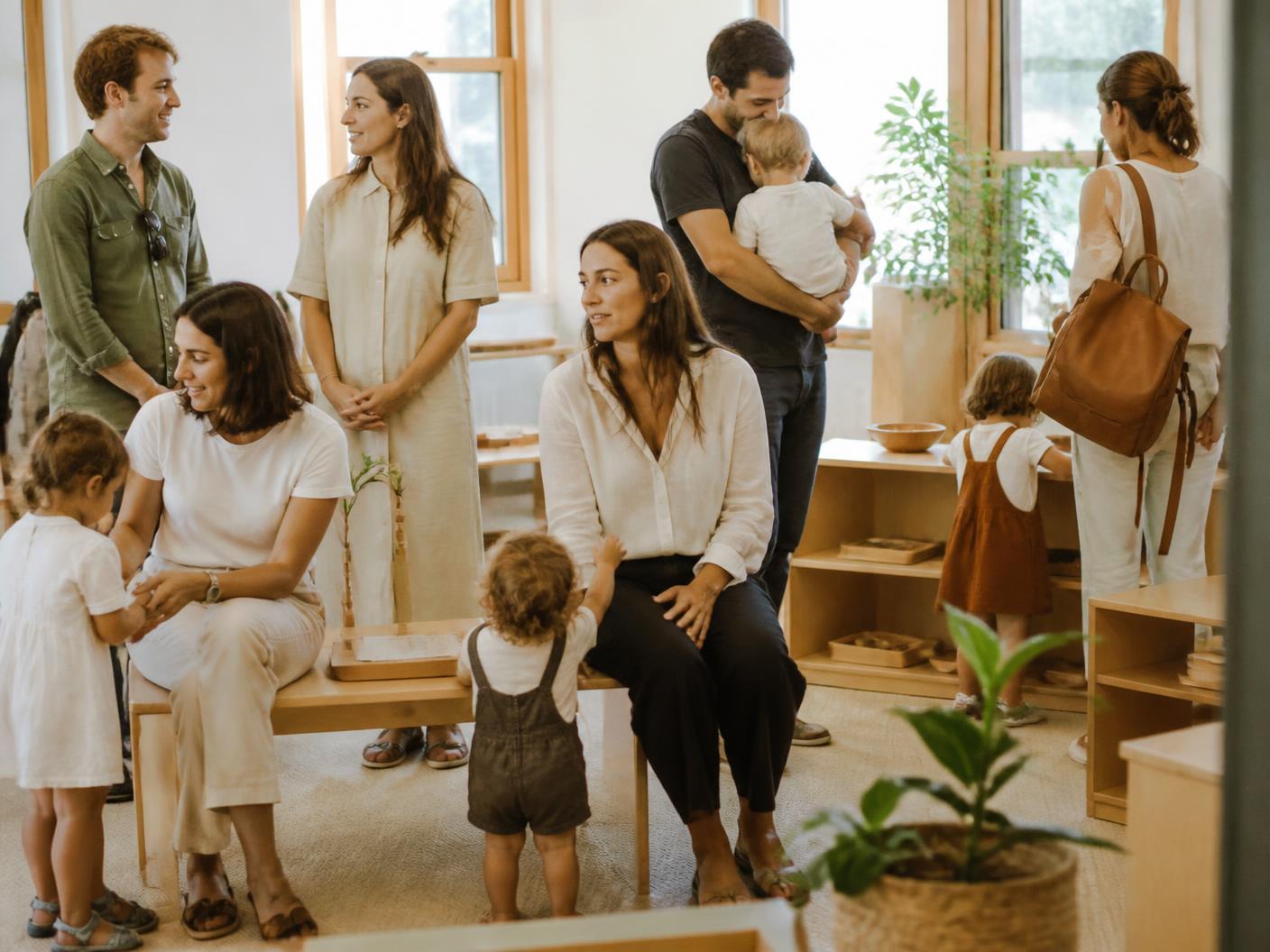 Familias y educadores compartiendo un momento cotidiano en un aula luminosa